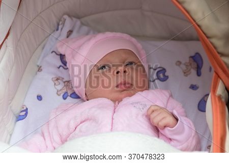 Baby In A Stroller In A Pink Jacket, Newborn Baby Girl In A Fluffy Pink Jacket Lies In A Stroller