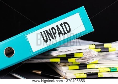 Text, Word Unpaid Is Written On A Folder Lying On Documents On An Office Desk. Business Concept.