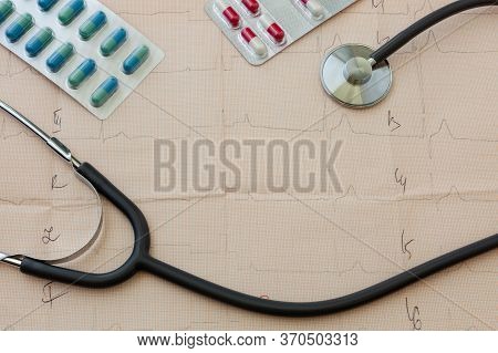 Medical Statoscope And Tablets Of Different Colors In Blisters On A Table With A Cardiologist Lies O