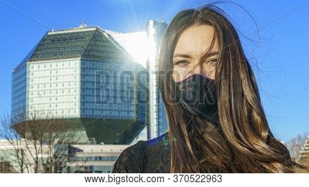 Portrait Of Brunette Woman In A Protective Medical Mask On A Cityscape Background. Virus Protection.