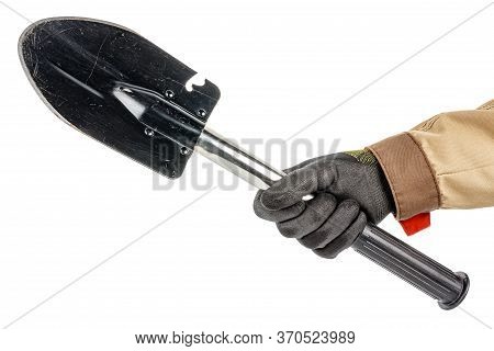 Black Folding Shovel With With Scratches And Scuffs In Male Hand In Black Protective Glove And Brown