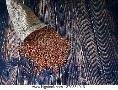 Spilling Of Buckwheat Grains From Burlap On A Wooden Table.