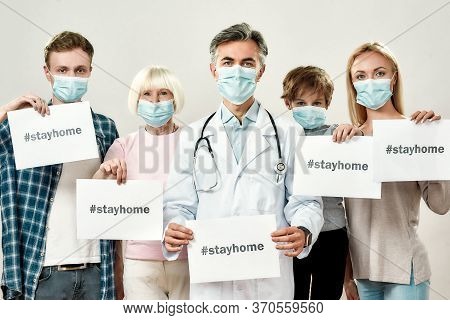 Stop Coronavirus. Portrait Of Mature Male Doctor And Family Of Four Wearing Medical Protective Masks