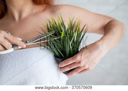 Faceless Red-haired Caucasian Woman Wrapped In A White Terry Towel Shears A Potted Plant With Scisso