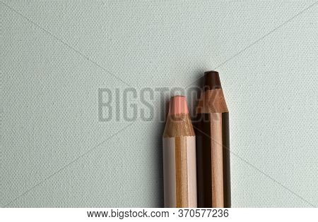 Two Pink And Brown Colored Pencils Standing Next To Each Other