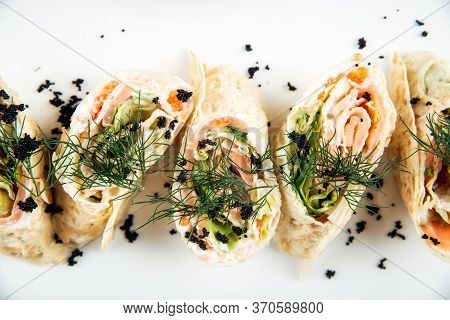 Top View Closeup On Gourmet Slapjack Rolls With Salmon Filling Black Caviar Dill Garnish On A White 
