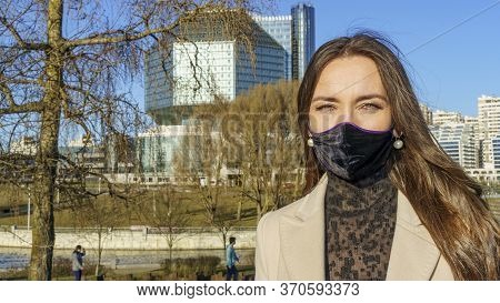 Portrait Of Brunette Woman In A Protective Medical Mask On A Cityscape Background. Virus Protection.