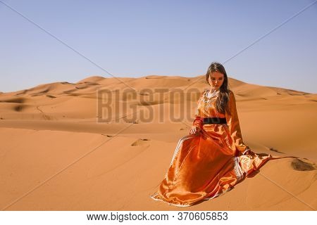 Beautiful Young Girl In Moroccan Dress In Sahara Desert.