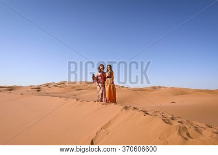 Girls In Moroccan Dress In Sahara Desert.
