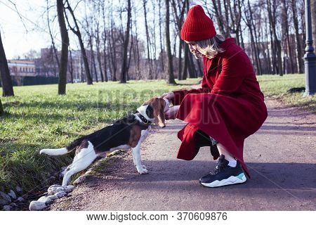 Pretty Young Girl In Redd Coat Playing With Dog Outside In Green Park, Lifestyle People Concept