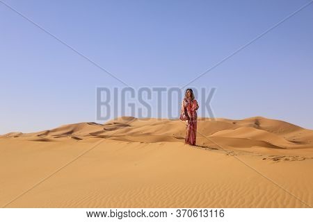 Girl In Moroccan Dress In Sahara Desert.