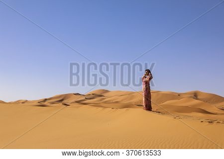 Girl In Moroccan Dress In Sahara Desert.