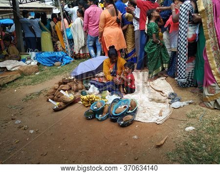 Indian Poor Mother And Child Selling Coconut, Lime, Banana And Flowers Or Puja Items In A Roadside N