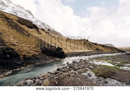 A Shallow Mountain River With Blue Azure Water Flows Against The Backdrop Of Mountains Into The Mth 