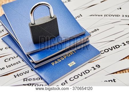 A Padlock And Passports On The Background Of Newspaper Headline Clippings. Coronavirus And Travel Co