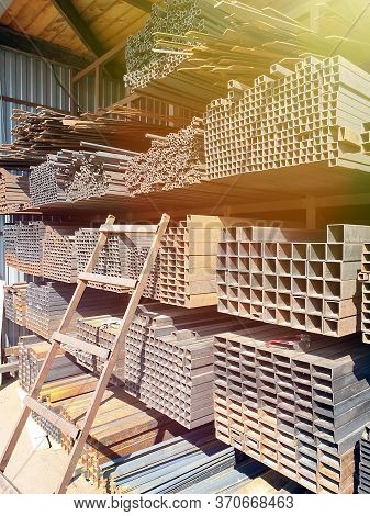 Construction Market. Racks With Metal Rods And Profiles With A Ladder Attached To Them