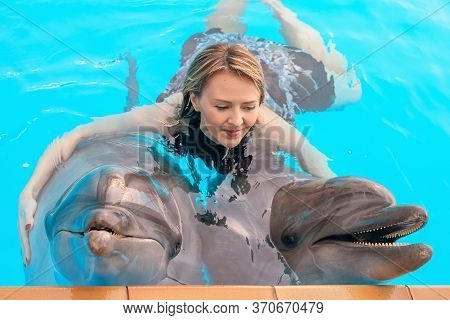 Young Girl Hugs Two Dolphins At The Dolphin Therapy Session