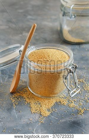 Jar Of Raw Amaranth Grain With A Spoon On Grey Table Close Up
