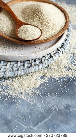 Raw Uncooked Fonio Seeds With A Spoon On A Plate On Grey Background Close Up With Copy Space
