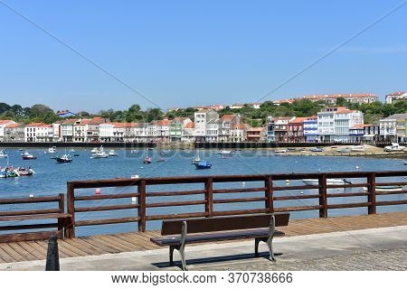 Mugardos, Spain. May 30, 2020. Fishing Village With Wooden Boardwalk, Bench And Boats With Blue Sky.