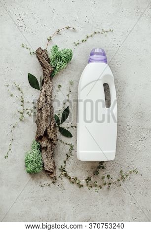 Composition With Bottle Of Laundry Detergent By Tree Bark, Tiny Mosses And Grass On Light Concrete B