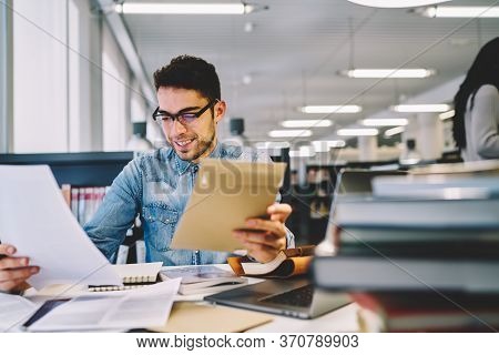 Smiling Male Student Making Coursework Project In College Library