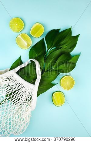 White Woven String Bag With Green Leaves Branch, Citrus Lime On Turquoise Green Mint Background. Org