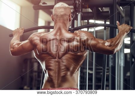 Muscular Bodybuilder Fitness Man Doing Pull-ups Exercises In Gym Naked Torso. Handsome Strong Athlet
