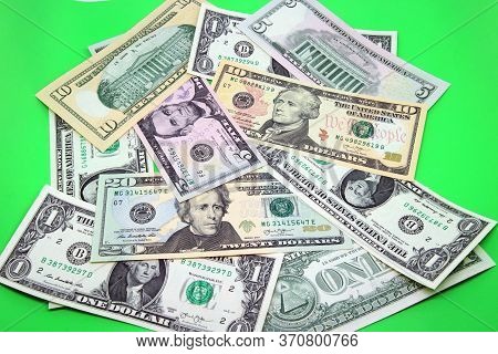 American Dollars Bills In Denominations Of 1, 5, 10 And 20 Scattered Out In A Bright Green Color Bac