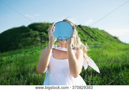 Woman Holds Mirror With Sky Reflection Instead Of Head. Concept Unity With Nature, Despair, Loneline