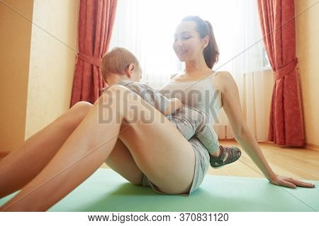 Mother With Baby Doing Gymnastics And Playing During Rest Break Time. Fitness Exercises With Childre