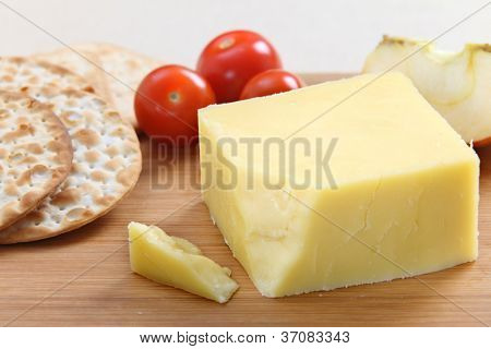 Ein Keil der englischen Cheddar-Käse mit Cracker und Cherry-Tomaten auf einer Käseplatte