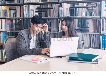High School Or College Students Studying And Reading Together In Library. Student Use Laptop At Libr