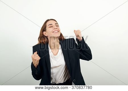 Arms Up Celebrating Success Fists In Exultation. Young Attractive Woman With Brown Hair In A Light T