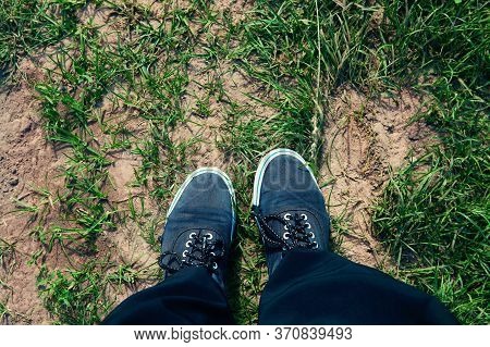 Legs In Sneakers On Road With Grass, Top View