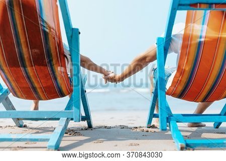 Couple Sitting On The Deck Chairs At The Beach. Honymoon, Love, Travel Or Vacation Concept.