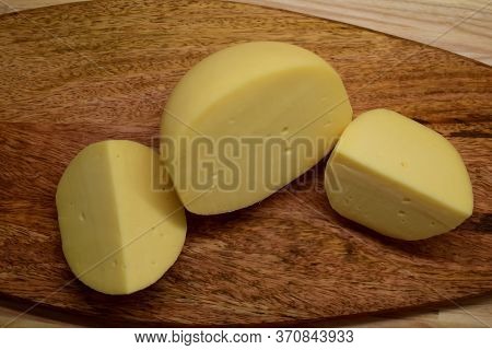 Edam Yellow Cheese Is Located On A Wooden Board.