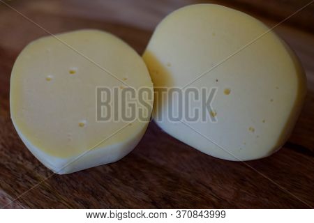 Edam Yellow Cheese Is Located On A Wooden Board.