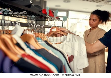 Cropped Shot Of Man Looking At Already Made Items, While Discussing Logo And Design Of T-shirt. Youn