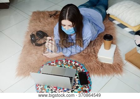 Young Woman In Medical Mask Successfully Working At Home Using Laptop. Concept Home Quarantine, Isol