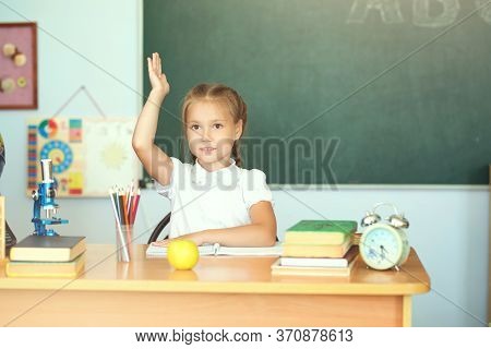 Cute Schoolgirl Pupil Raising Hand In Classroom