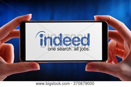 Hands Holding Smartphone Displaying Logo Of Indeed