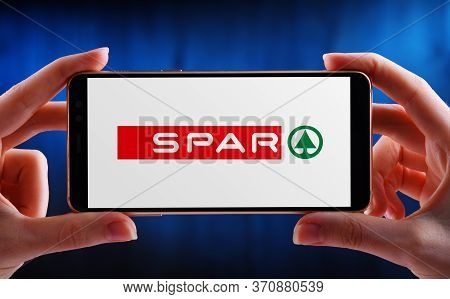 Hands Holding Smartphone Displaying Logo Of Spar