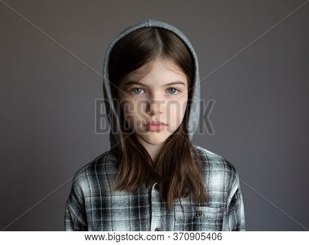 Portrait Of A Young Serious Girl In A Hoodie On A Dark Background