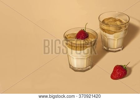 Dalgon Coffee In A Transparent Glass With Milk On A Pastel Background With Strawberries.