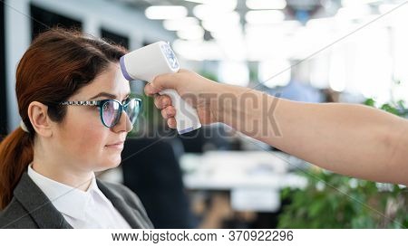 Temperature Measurement By Electronic Infrared Thermometer For Office Staff. Sick Woman In A Suit. C