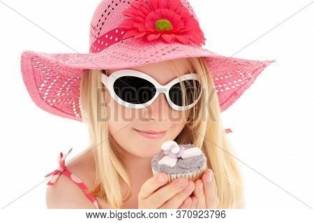 Beautiful Young Blonde Girl In Big Pink Floppy Hat And White Framed Sun Glasses Looking At A Cup Cak