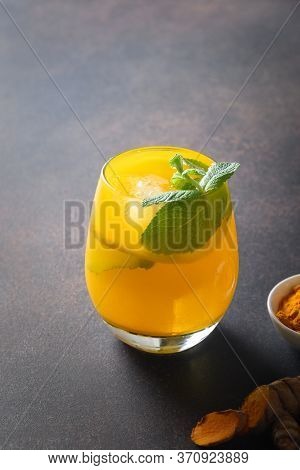 Jamu Indonesian Herbal Beverage In Bottle With Natural Ingredients Turmeric, Ginger, Lime On Brown B