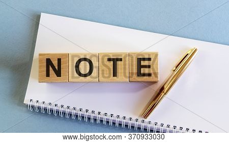 Wooden Cubes With Word Note On White Planner With Golden Pen On Blue Table. Note Concept. Nb Concept