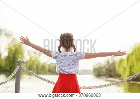 Girl Teenager Standing Near The River On The Pier, Raised Her Hands To The Top, Enjoys The Good Weat